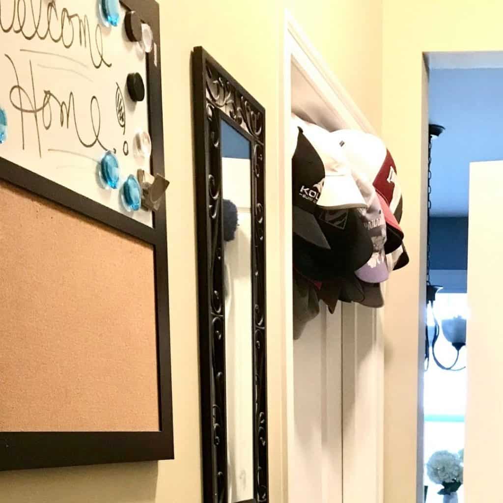 turning closet into mudroom with a message board, mirror, and over the door ball cap hooks