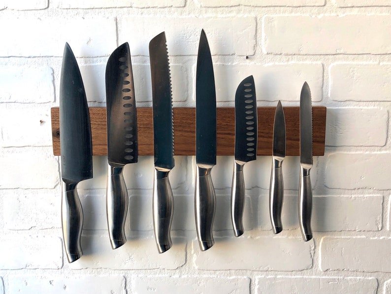 wooden magnetic knife holder holding 7 knives of various sizes
