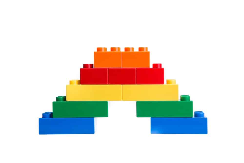 multi colored legos stacked in an arch on white background