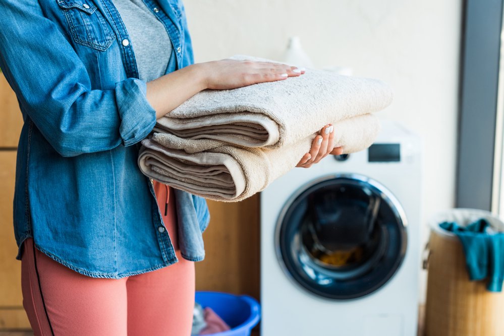 fabric softener substitute lady holding towels next to a dryer