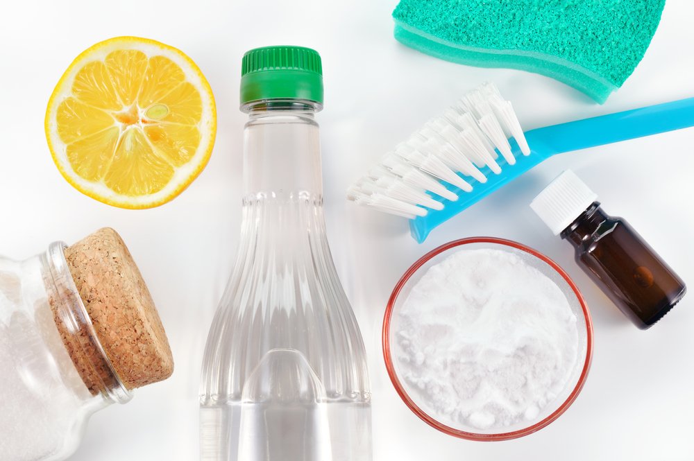 fabric softener substitutes in photo like vinegar with green cap and baking soda in a small dish and a lemon