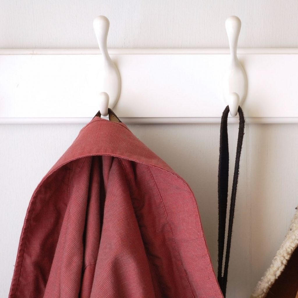 hooks with mauve colored coat and purse strap hanging from them for 1 of 5 ways to organize messy stairs