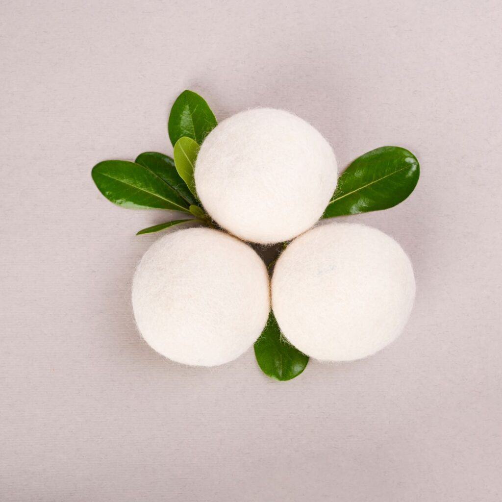 three wool dryer balls with leaves in between