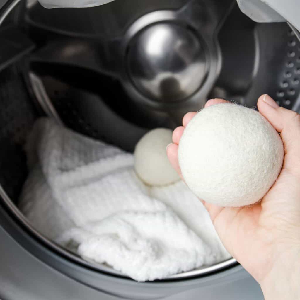 womans hand placing wool dryer balls into dryer